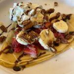 Crepe covered with strawberries, bananas, walnuts, whip cream, chocolate drizzle