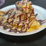 Crepe covered with powdered sugar, sprinkles and chocolate drizzle