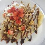 Crepe covered in strawberries, granola, whipped cream and chocolate drizzle